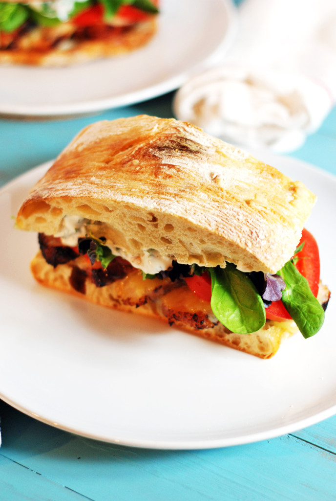 Crispy Pork Belly Sandwich: Tasty pork belly is the star of this sandwich, where it is paired with roasted garlic cilantro aioli, white cheddar cheese, and fresh tomatoes and greens.