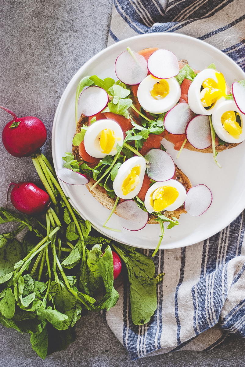 The perfect lunch: egg and cured salmon sandwiches featuring soft boiled eggs, cured salmon, fresh radishes and arugula, and a mustard sauce.
